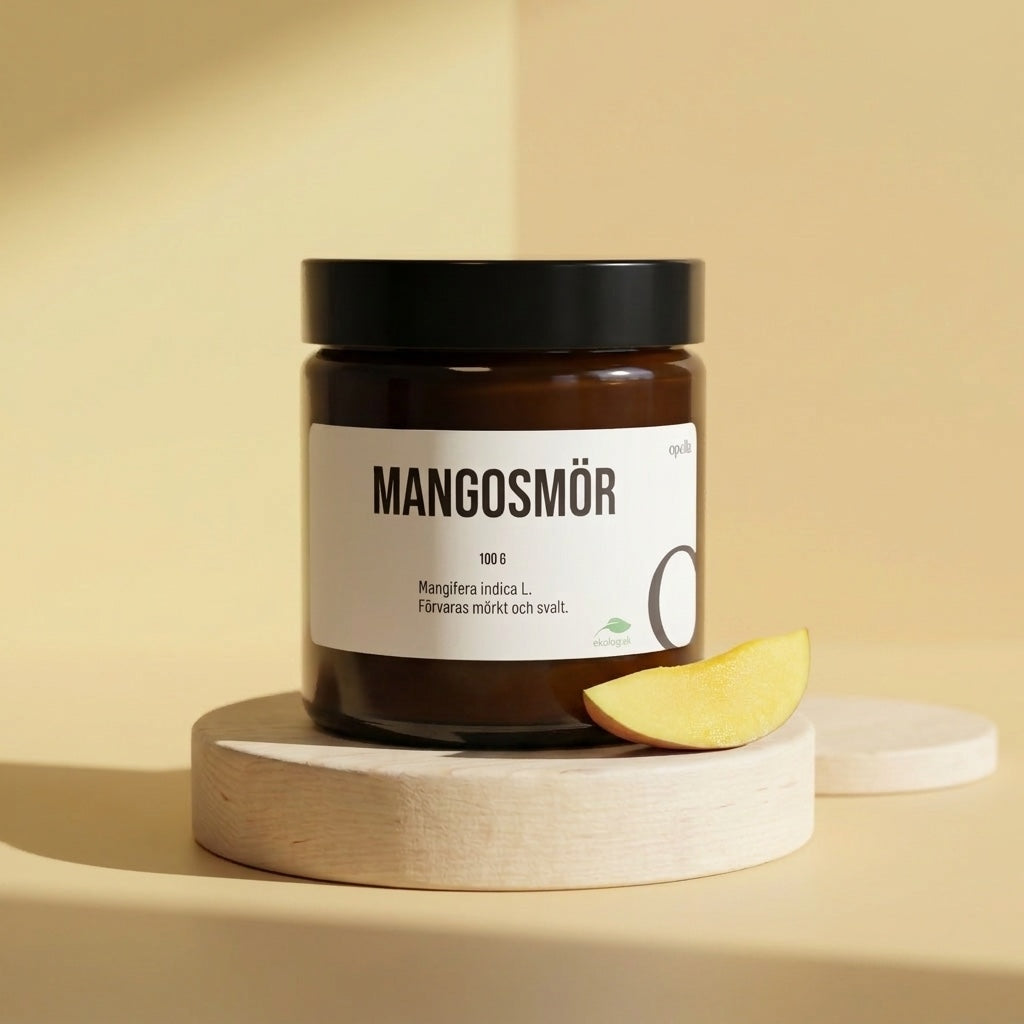 Burk med ekologiskt mangosmör och en skiva mango mot varm gul bakgrund